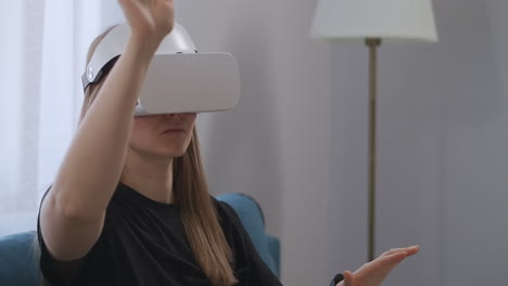 using-head-mounted-display-by-young-female-user-at-home-viewing-screen-and-pressing-virtual-buttons-young-lady-with-VR-headset-in-room